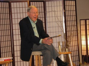 Glasser on a stool, his water beside him, giving a talk in Ventura (c. 2006)